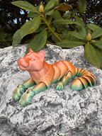 Colorful dinosaur toy on a rock with green leaves in the background