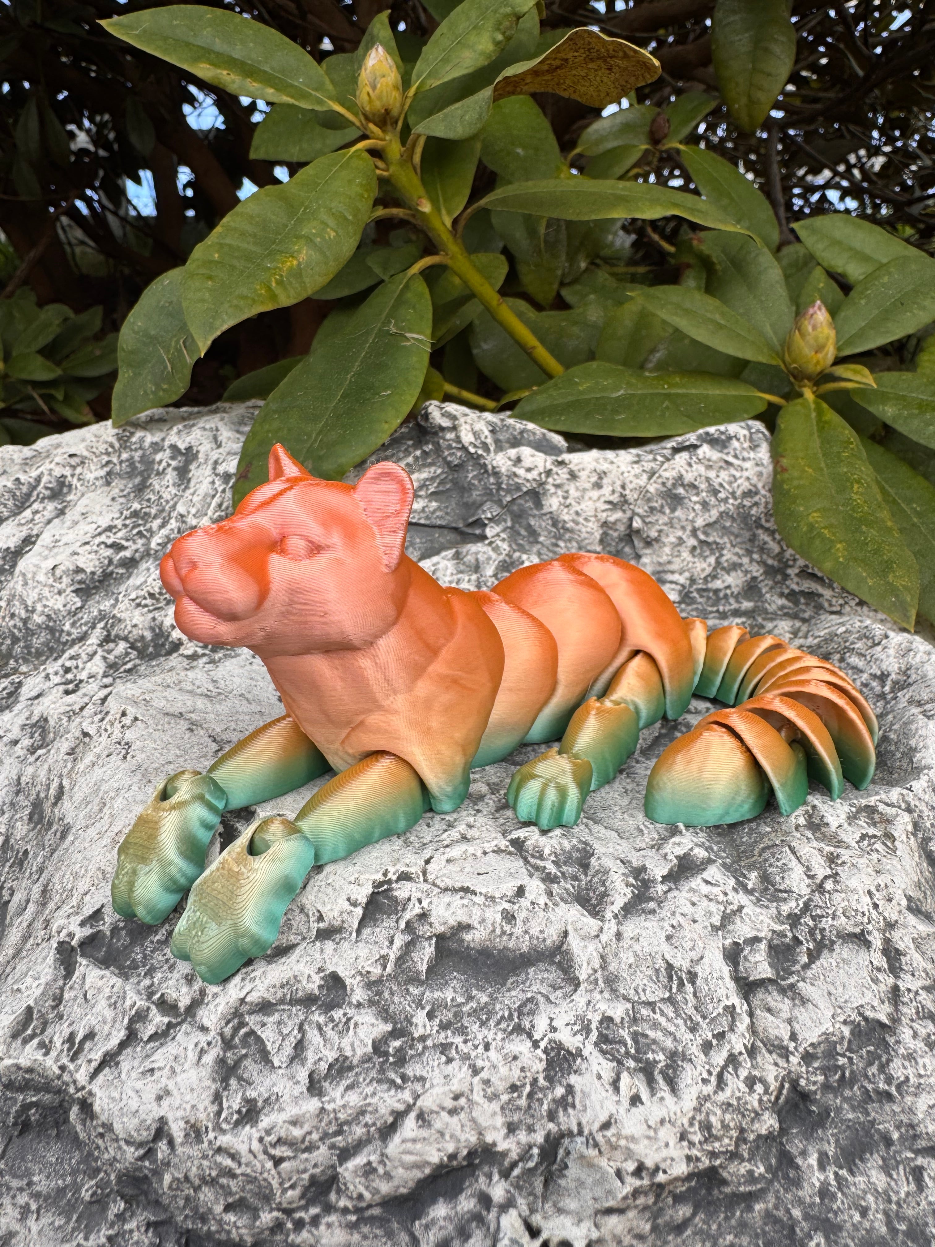 Colorful dinosaur toy on a rock with green leaves in the background